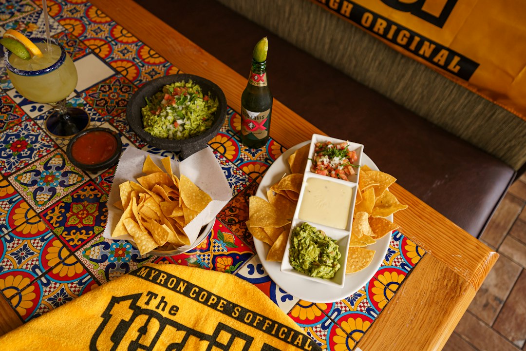 FootballR - NFL - Diese Beschreibung wurde automatisch generiert. Guacamole, Chips und Salsa auf einem Tisch.