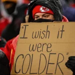 FootballR - NFL - In Kansas City hält ein Mann ein Schild hoch, auf dem er seinen Wunsch nach kälteren Temperaturen zum Ausdruck bringt.