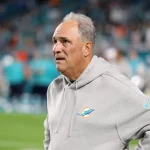 FootballR - NFL - Diese Beschreibung wurde automatisch generiert. Ein Trainer der Miami Dolphins, Vic Fangio, schaut während eines Spiels zu.