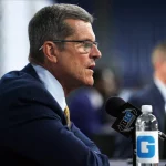 FootballR - NFL - Offseason-Programm - Diese Beschreibung wurde automatisch generiert. Ein Mann in Anzug und Krawatte, Jim Harbaugh, spricht in ein Mikrofon über die NFL und die Los Angeles Chargers.