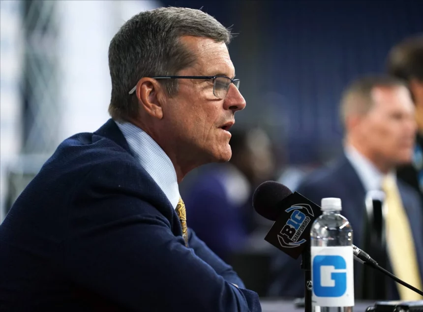 FootballR - NFL - Offseason-Programm - Diese Beschreibung wurde automatisch generiert. Ein Mann in Anzug und Krawatte, Jim Harbaugh, spricht in ein Mikrofon über die NFL und die Los Angeles Chargers.