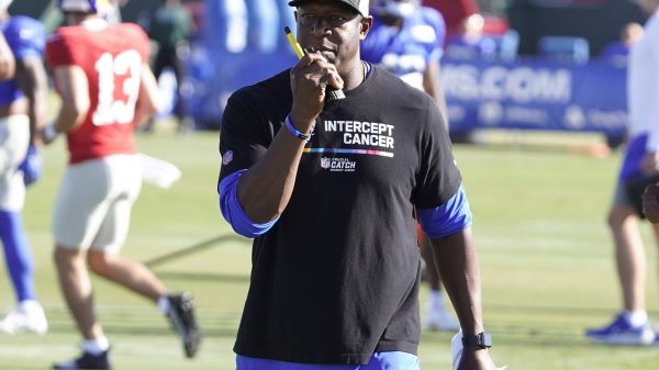 FootballR - NFL - Diese Beschreibung wurde automatisch generiert. Raheem Morris, der Cheftrainer der Atlanta Falcons, trägt ein schwarzes Hemd.