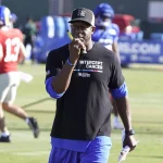 FootballR - NFL - Diese Beschreibung wurde automatisch generiert. Raheem Morris, der Cheftrainer der Atlanta Falcons, trägt ein schwarzes Hemd.