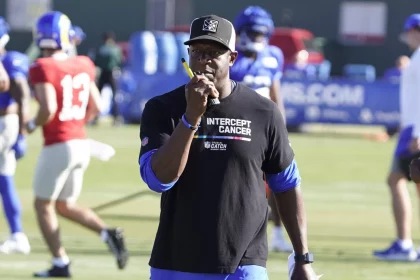 FootballR - NFL - Diese Beschreibung wurde automatisch generiert. Raheem Morris, der Cheftrainer der Atlanta Falcons, trägt ein schwarzes Hemd.