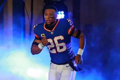 FootballR - NFL - Diese Beschreibung wurde automatisch generiert. Saquon Barkley, ein Running Back der Giants, in blauer Uniform, rennt durch Rauch.
