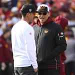 FootballR - NFL - Ron Rivera, Cheftrainer der Washingtoner Fußballmannschaft, unterhält sich auf einem Fußballfeld mit einem anderen Mann.