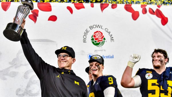 FootballR - NFL - Jim Harbaugh - Die Footballspieler der Michigan Wolverines heben triumphierend die Rose Bowl Trophäe in die Höhe.