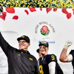 FootballR - NFL - Jim Harbaugh - Die Footballspieler der Michigan Wolverines heben triumphierend die Rose Bowl Trophäe in die Höhe.