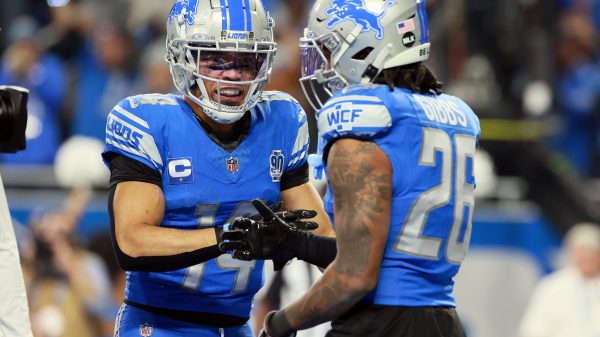 FootballR - NFL - Zwei Footballspieler der Detroit Lions in blauen und silbernen Uniformen treten in einem dramatischen Wild Card Game gegen die Rams an. Amon-Ra St. Brown