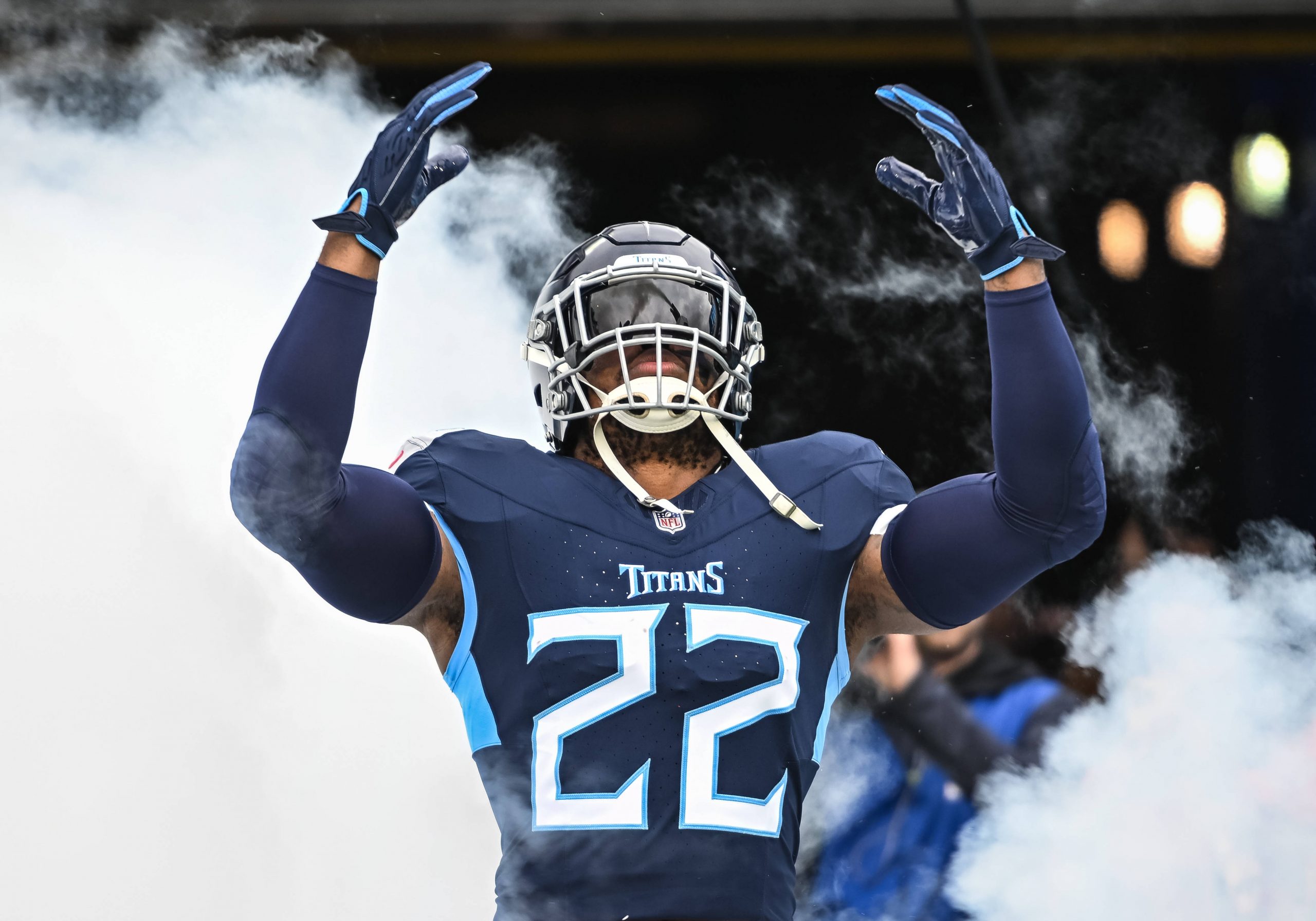 FootballR - NFL - Diese Beschreibung wurde automatisch generiert. Ein Titans-Spieler in einer blauen Uniform, steht vor Rauch. Gibt es die Derrick Henry Rückkehr ins Team?