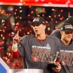 FootballR - NFL - Diese Beschreibung wurde automatisch generiert. Die San Francisco 49ers halten stolz ihre NFC Trophäe in der Hand. Weiter geht's in den Super Bowl LVIII