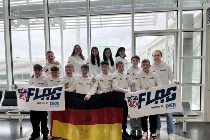 FootballR - NFL - Diese Beschreibung wurde automatisch generiert. Eine Gruppe von Menschen posiert für ein Foto mit einer deutschen Flagge, die ein Flag Football Team repräsentiert.