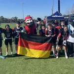 FootballR - NFL - Diese Beschreibung wurde automatisch generiert. Mitglieder des Deutschen Flag Football Teams posieren mit einer deutschen Flagge während der Pro Bowl Games.