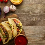 FootballR - NFL - Diese Beschreibung wurde automatisch generiert. Super Bowl Bite mit mexikanischen Tacos auf einem Holzschneidebrett.