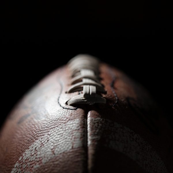 FootballR - NFL Franchise Tag - Diese Beschreibung wurde automatisch generiert. Eine Nahaufnahme, die einen Football vor einem schwarzen Hintergrund zeigt.