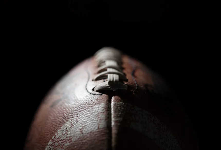 FootballR - NFL Franchise Tag - Diese Beschreibung wurde automatisch generiert. Eine Nahaufnahme, die einen Football vor einem schwarzen online Casinos Hintergrund zeigt.