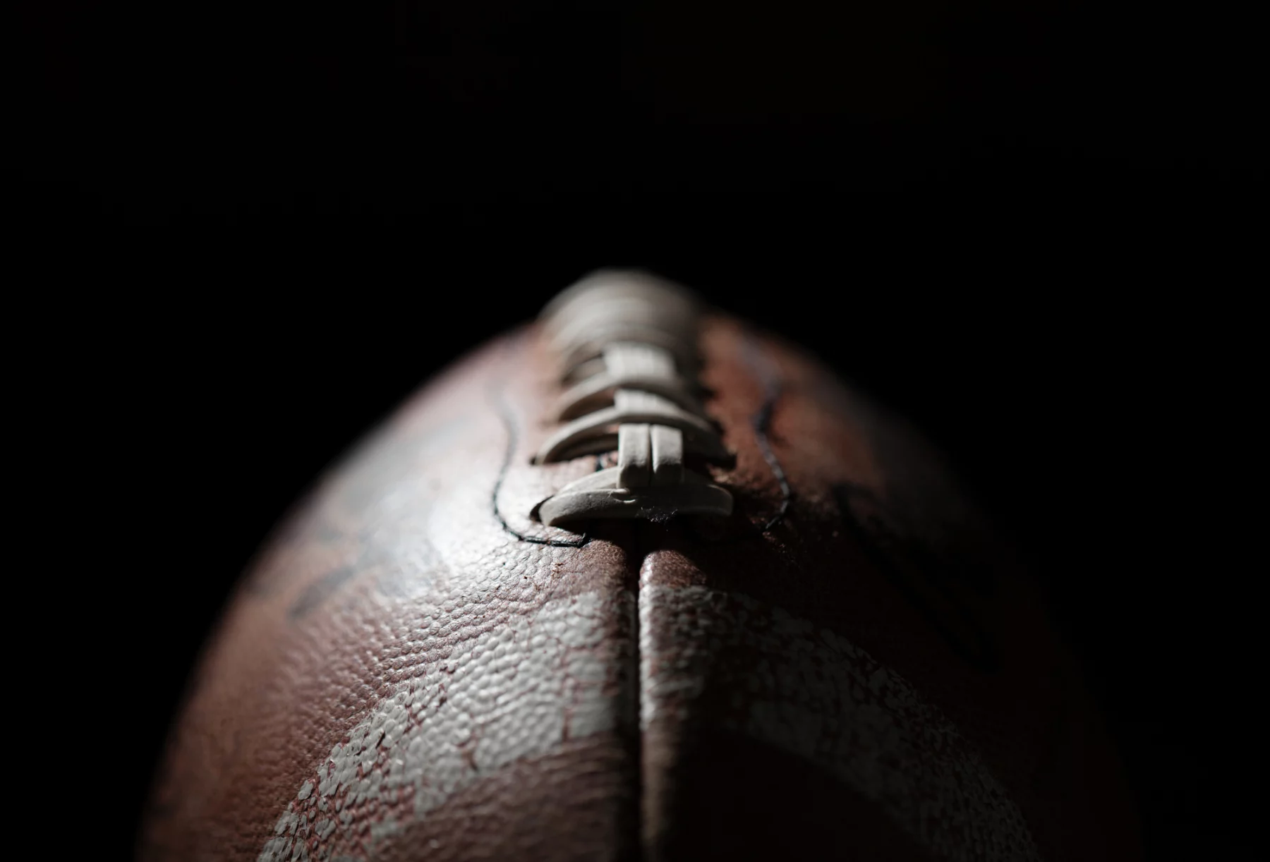 FootballR - NFL Franchise Tag - Diese Beschreibung wurde automatisch generiert. Eine Nahaufnahme, die einen Football vor einem schwarzen online Casinos Hintergrund zeigt.