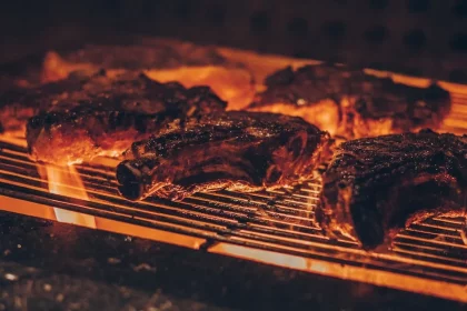 FootballR - NFL - Diese Beschreibung wurde automatisch generiert. Fleisch auf einem Grill mit Flammen.