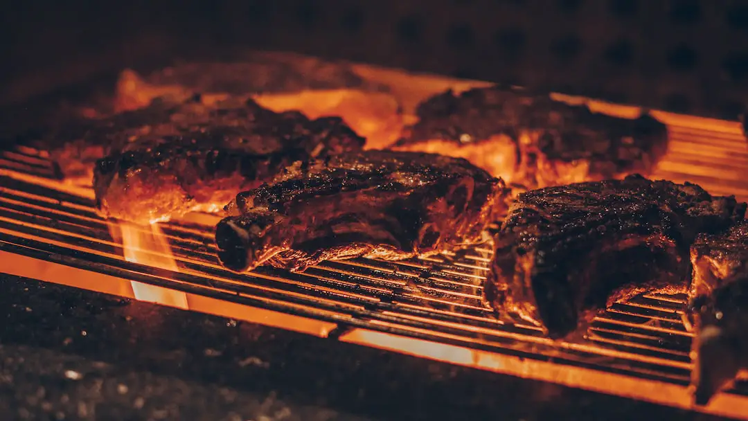 FootballR - NFL - Diese Beschreibung wurde automatisch generiert. Fleisch auf einem Grill mit Flammen.