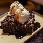 FootballR - NFL - Diese Beschreibung wurde automatisch generiert. Ein Brownie mit Eis auf einem Teller.