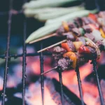 FootballR - NFL - Diese Beschreibung wurde automatisch generiert. Spieße mit Fleisch und Gemüse auf dem Grill.