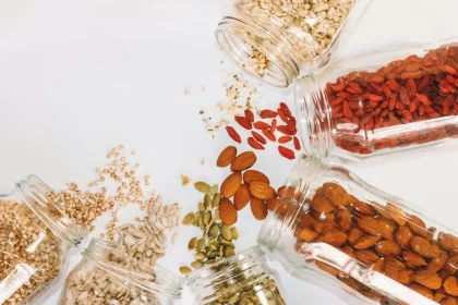 FootballR - NFL - Diese Beschreibung wurde automatisch generiert. Verschiedene Nüsse und Samen in Gläsern auf weißem Hintergrund.