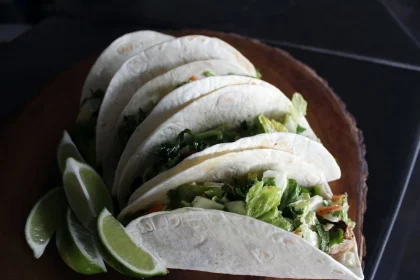 FootballR - NFL - Diese Beschreibung wurde automatisch generiert. Vier Tacos auf einem Holzteller mit Limettenspalten.