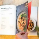 FootballR - NFL - Diese Beschreibung wurde automatisch generiert. Eine Person hält ein Buch mit einem Bild von Lebensmitteln.