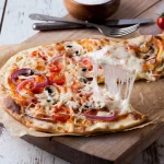 FootballR - NFL - Diese Beschreibung wurde automatisch generiert. Eine Pizza mit Käse und Pilzen auf einem Holzbrett.