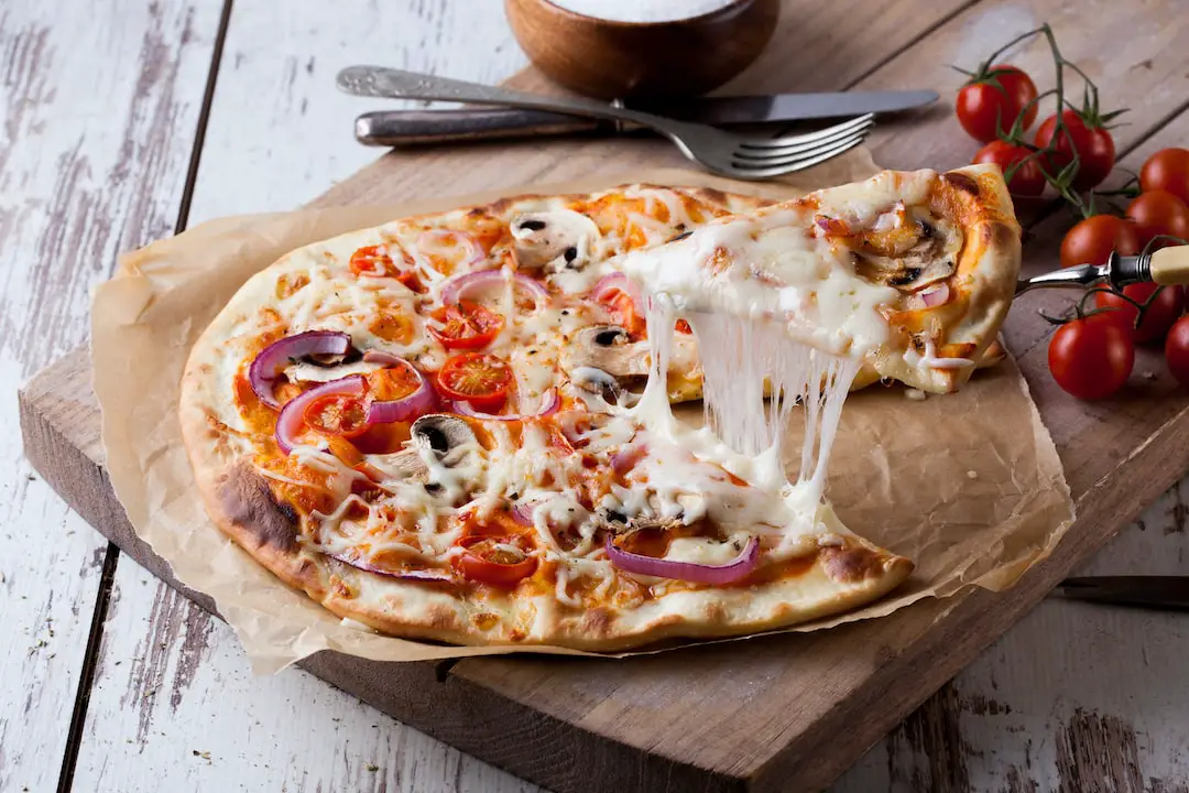 FootballR - NFL - Diese Beschreibung wurde automatisch generiert. Eine Pizza mit Käse und Pilzen auf einem Holzbrett.
