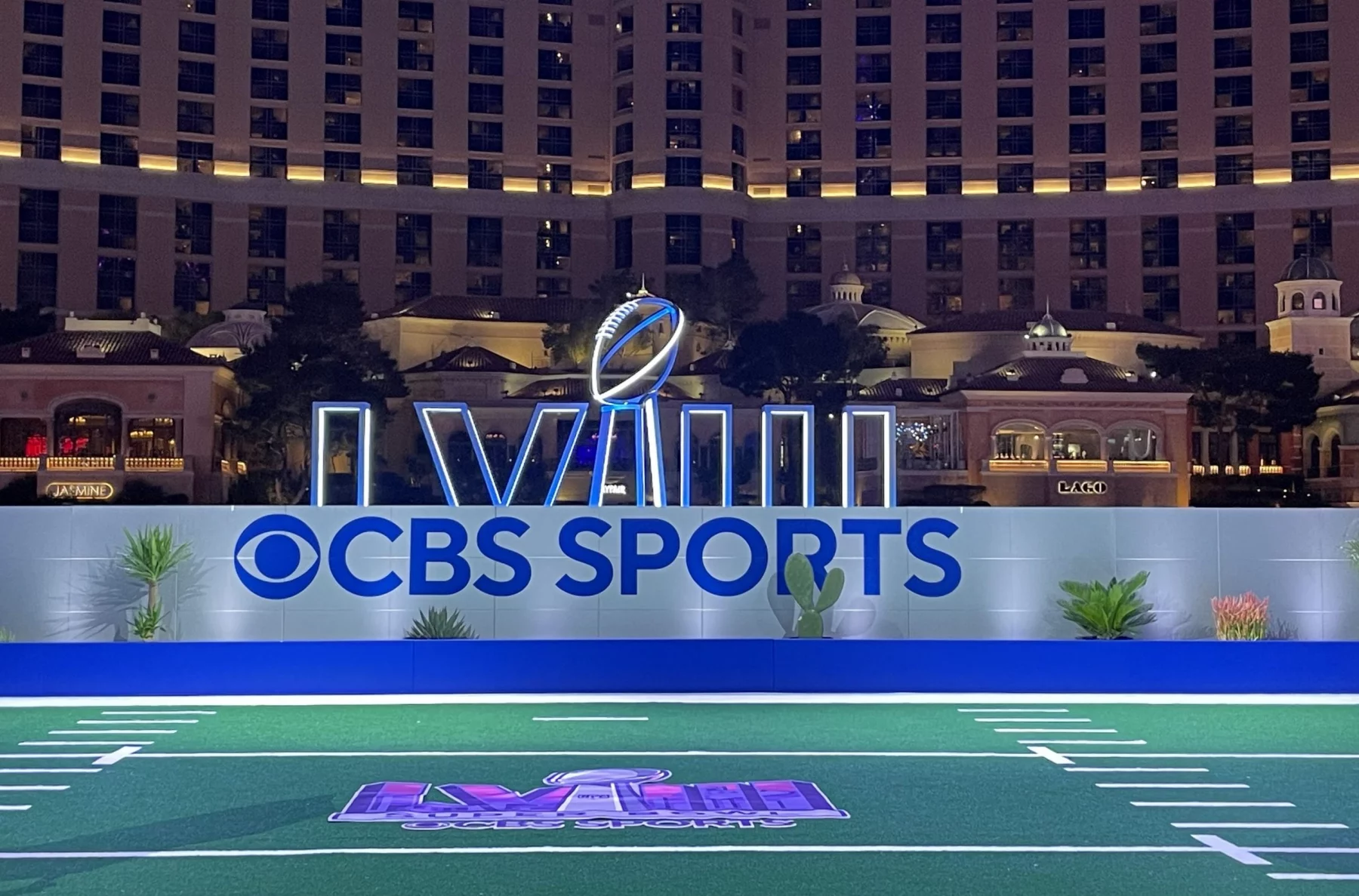 FootballR - NFL - Diese Beschreibung wurde automatisch generiert. Das CBS-Sportlogo befindet sich auf einem Footballfeld in Las Vegas. Super Bowl LVIII Tipping Game