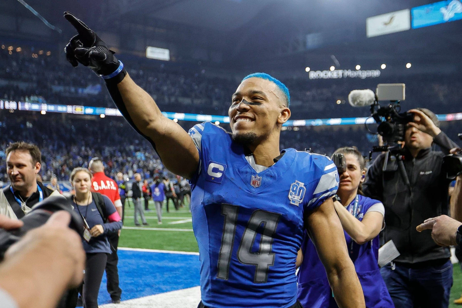 FootballR - NFL - Diese Beschreibung wurde automatisch generiert. Ein Footballspieler der Detroit Lions mit blauen Haaren, Amon-Ra St. Brown. Er sprach über den Verbleib von Ben Johnson
