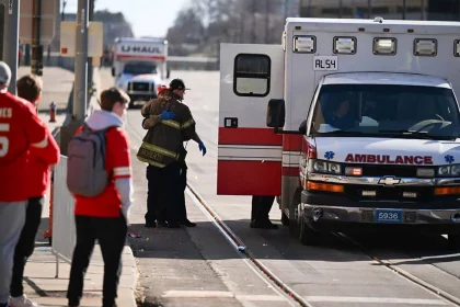 FootballR - NFL Super-Bowl-Parade - Diese Beschreibung wurde automatisch generiert. Eine Gruppe Jugendlicher steht neben einem Krankenwagen auf einer Straße.
