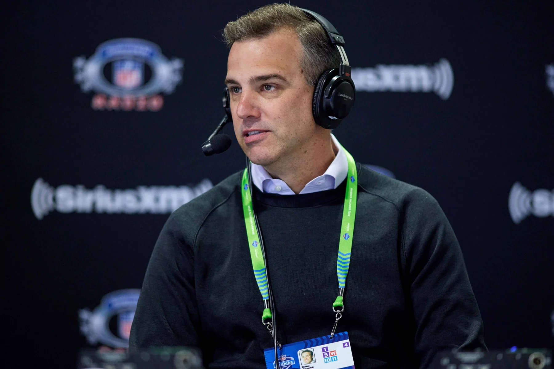 FootballR - NFL - Diese Beschreibung wurde automatisch generiert. Ein Mann, der mit Kopfhörern vor einem Mikrofon sitzt, Daniel Jeremiah.