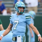 FootballR - NFL - Diese Beschreibung wurde automatisch generiert. Michael Pratt, ein Footballspieler in blauer Uniform, wirft einen Ball auf das Spielfeld.