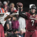 FootballR - NFL - Die besten noch verfügbaren Spieler - Diese Beschreibung wurde automatisch generiert. Spencer Rattler, ein Footballspieler, wirft während eines Spiels einen Ball.