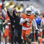 FootballR - NFL - Diese Beschreibung wurde automatisch generiert. Chau Smith-Wade, ein Footballspieler, der am Senior Bowl teilnimmt, sprintet zusammen mit anderen Spielern während eines Abfangspiels.