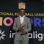 MVP Finalisten - NFL MVP Rennen 2024 - Pro Bowl Abstimmung 2025 - Diese Beschreibung wurde automatisch generiert. Lamar Jackson, der NFL MVP 2023, hält stolz seine Auszeichnung für seine bemerkenswerte Leistung in der National Football League.