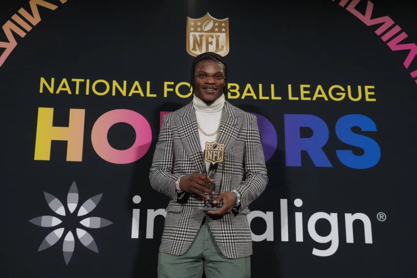 MVP Finalisten - NFL MVP Rennen 2024 - Pro Bowl Abstimmung 2025 - Diese Beschreibung wurde automatisch generiert. Lamar Jackson, der NFL MVP 2023, hält stolz seine Auszeichnung für seine bemerkenswerte Leistung in der National Football League.