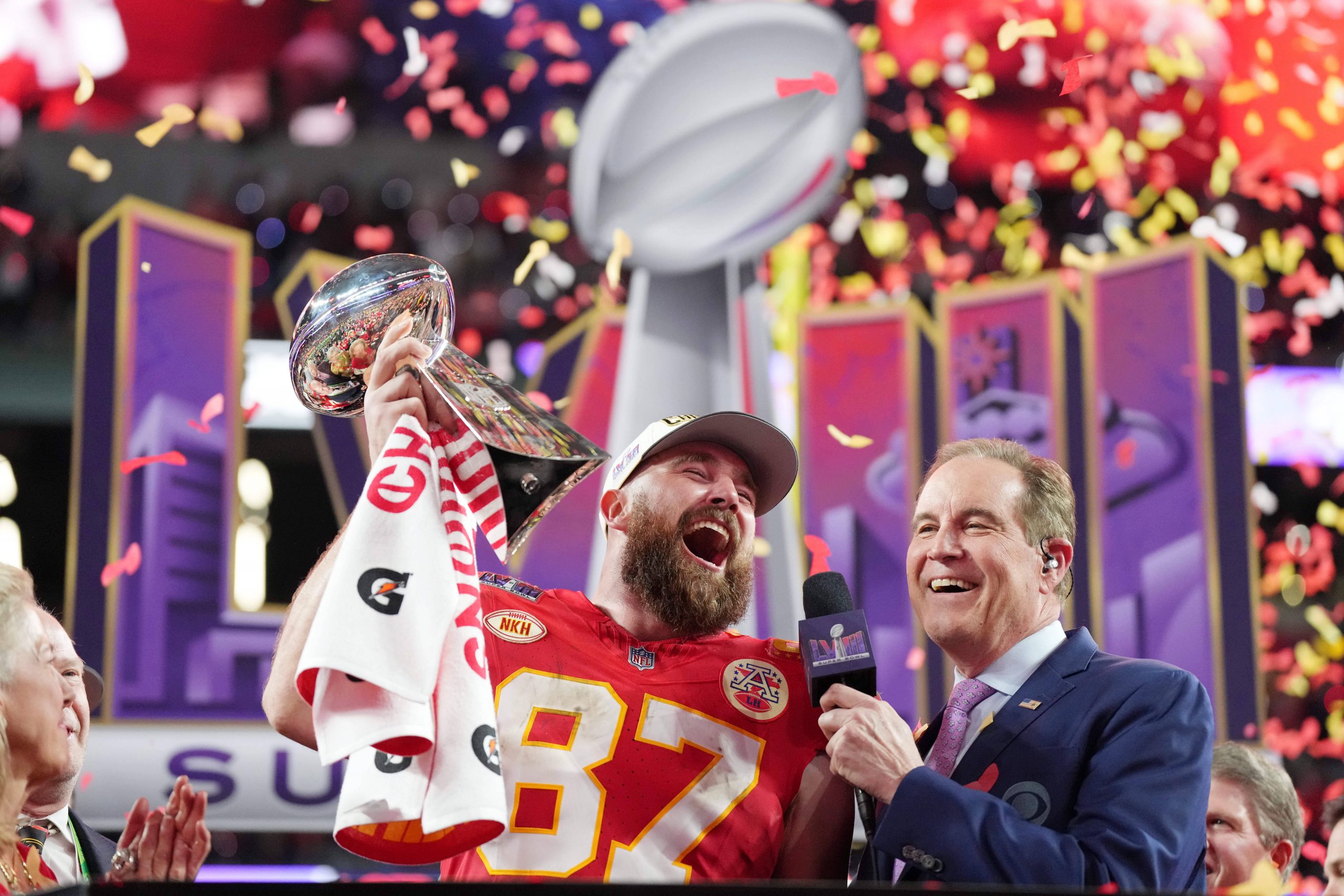 FootballR - NFL - Diese Beschreibung wurde automatisch generiert. Super Bowl Overtime - Ein Mann hält eine Trophäe und ein anderer Mann hält ein Mikrofon und feiern ihren Sieg beim Super Bowl. CBS