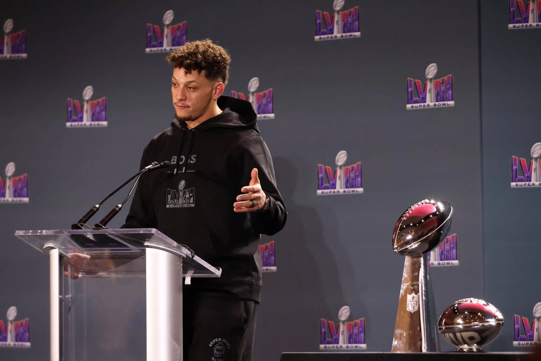 FootballR - NFL - Diese Beschreibung wurde automatisch generiert. Ein Mann, Patrick Mahomes, steht mit einer Trophäe vor sich auf einem Podium und feiert den Sieg im Super Bowl LVIII mit rekordverdächtiger Zuschauerzahl.