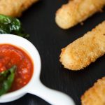 FootballR - NFL - Diese Beschreibung wurde automatisch generiert. Mozzarella-Spieße mit Marinara-Dip auf einem Teller, perfekt für den Super Bowl.