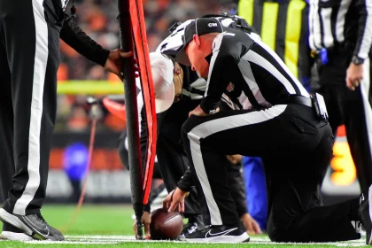 FootballR - NFL Hawk Eye - Diese Beschreibung wurde automatisch generiert. Ein NFL-Schiedsrichter kniet auf dem Spielfeld und nutzt dabei High-Tech Tracking Geräte.