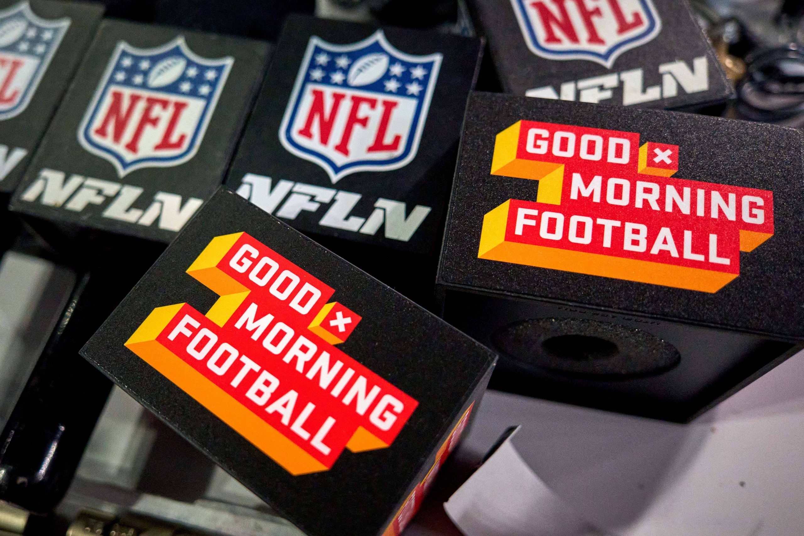 FootballR - NFL - Diese Beschreibung wurde automatisch generiert. NFL-Show Good Morning Football Logos auf einem Tisch.