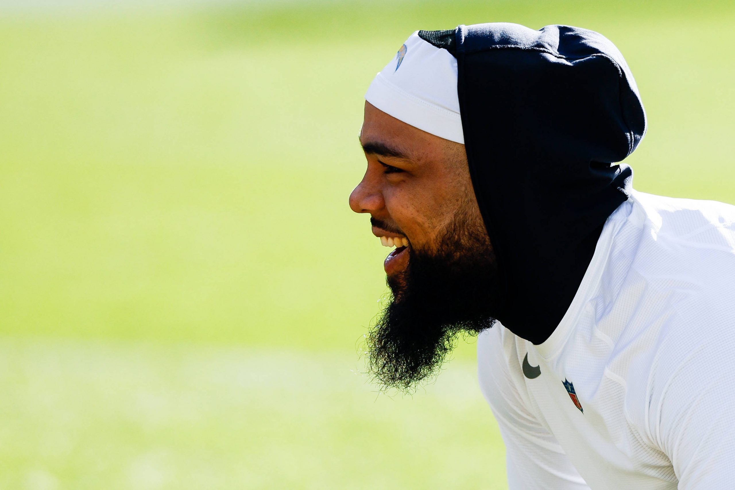 FootballR - NFL - Diese Beschreibung wurde automatisch generiert. Keenan Allen, ein Mann mit Bart, der an einem sonnigen Tag lächelt, ein Stirnband und Sportkleidung trägt.