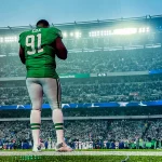 FootballR - NFL - Diese Beschreibung wurde automatisch generiert. Ein Eagles-Footballspieler, Fletcher Cox, steht auf einem Feld in einem Stadion.