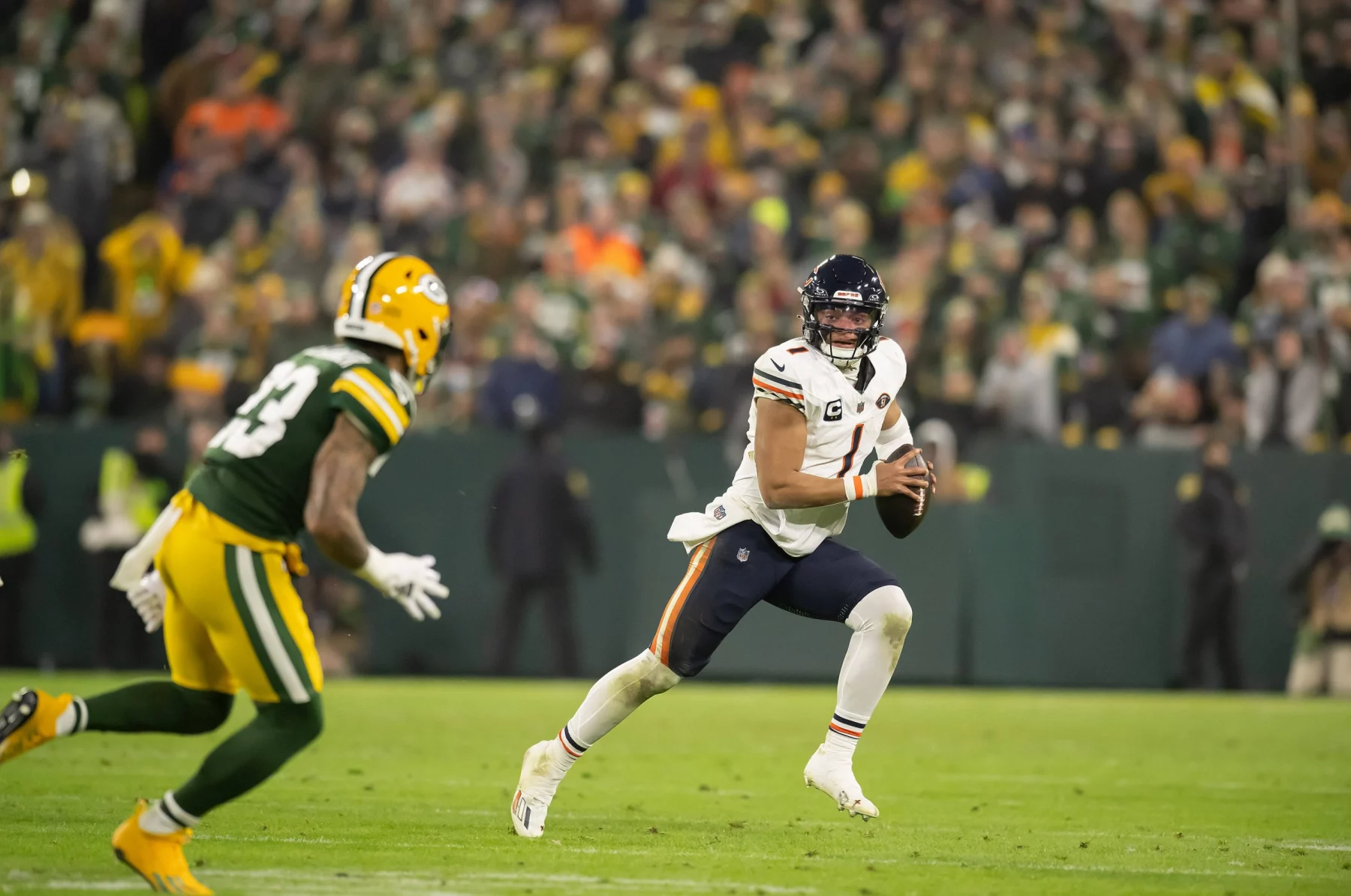 FootballR - NFL - Diese Beschreibung wurde automatisch generiert. Quarterback Justin Fields weicht einem Tackle während eines Footballspiels aus.