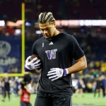 FootballR - NFL - Diese Beschreibung wurde automatisch generiert. Rome Odunze, ein Footballspieler, stolziert anmutig über das Spielfeld, seine Dreadlocks hinter sich herziehend.