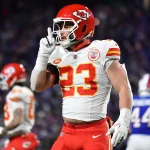 FootballR - NFL - Diese Beschreibung wurde automatisch generiert. Ein Footballspieler der Chiefs, Drue Tranquill, hält seine Hand hoch.