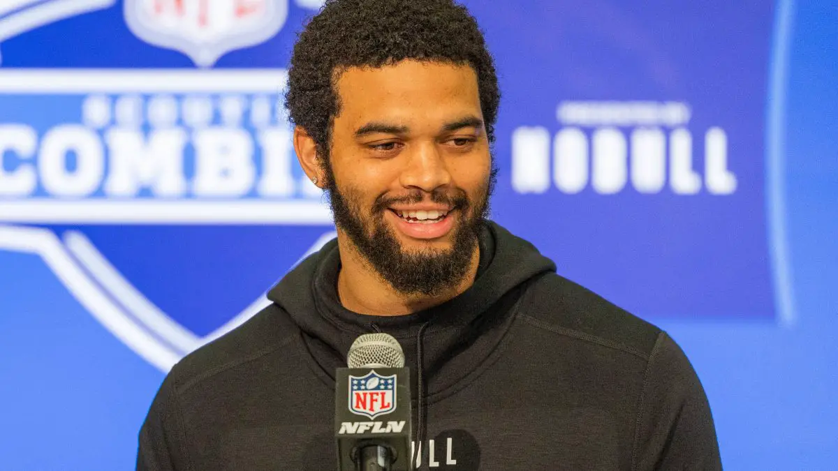 FootballR - NFL - Diese Beschreibung wurde automatisch generiert. Ein Mann mit Bart, Caleb Williams, lächelt während des NFL Combine in ein Mikrofon.